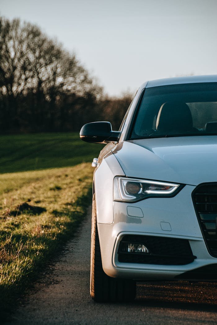 why-choose-us-02 Close-up of a sleek car parked on a quiet rural road during daytime.